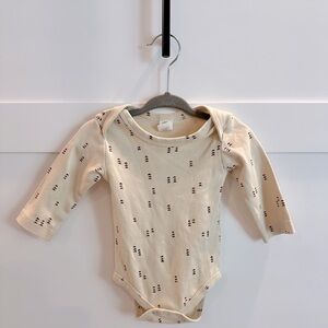 Colored organic cream long sleeve bodysuit with rust arrows.